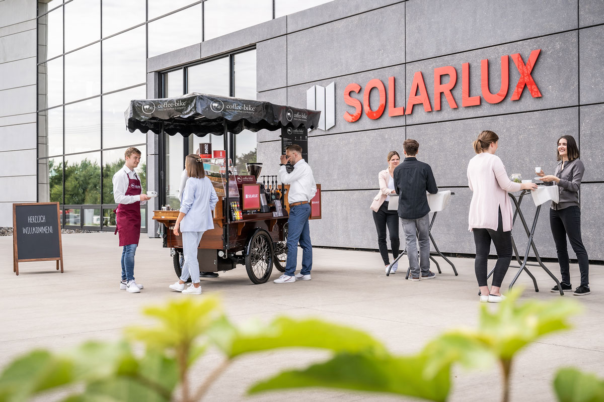 Event Catering Situation vor dem Solarlux Unternehmensgebäude mit Mitarbeitern, die Kaffee trinken und Gespräche vor der mobilen Kaffeebar halten